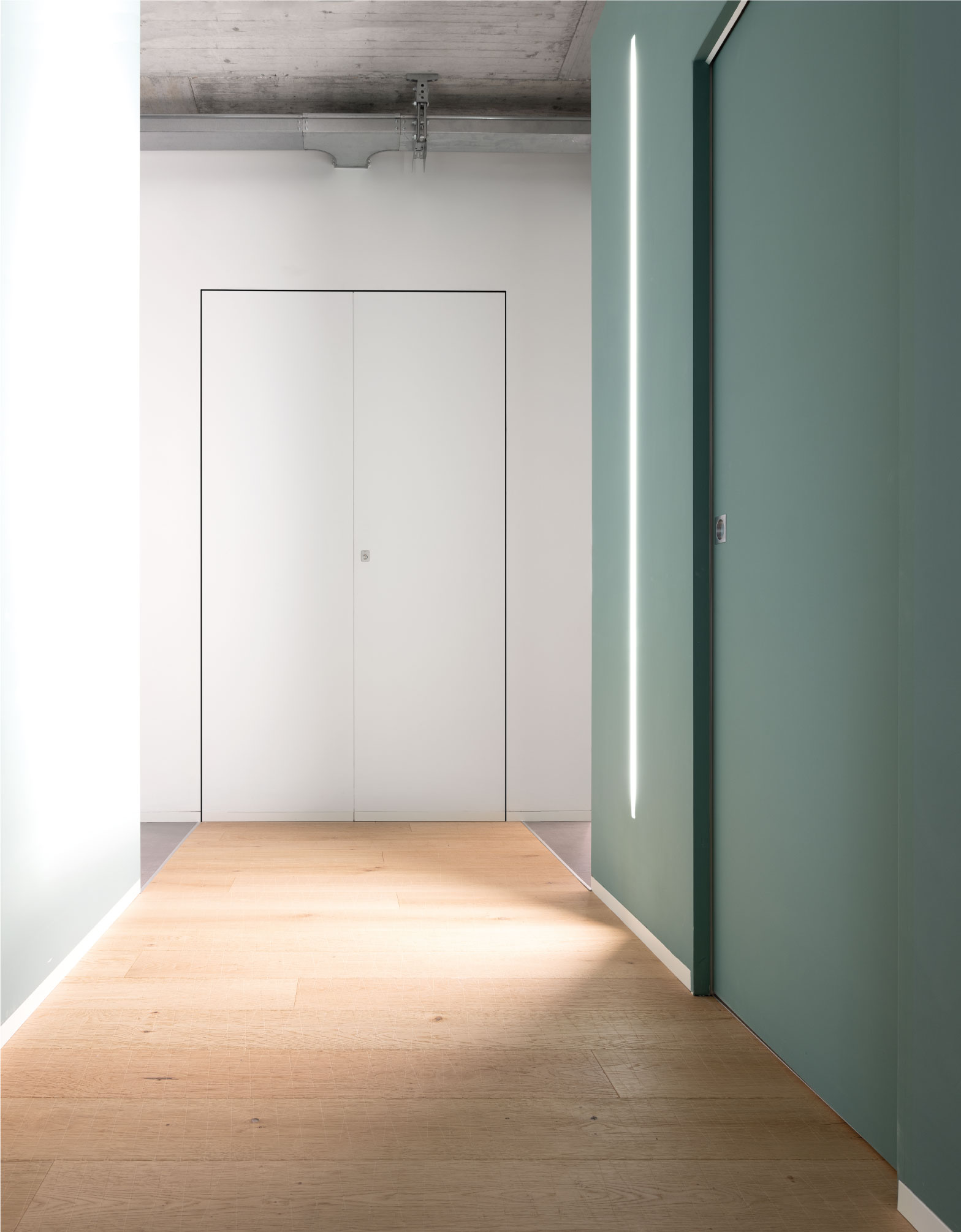Couloir donnant sur des portes coulissantes Syntesis® Line. L'un en bleu pour se fondre dans le mur et l'autre en blanc.