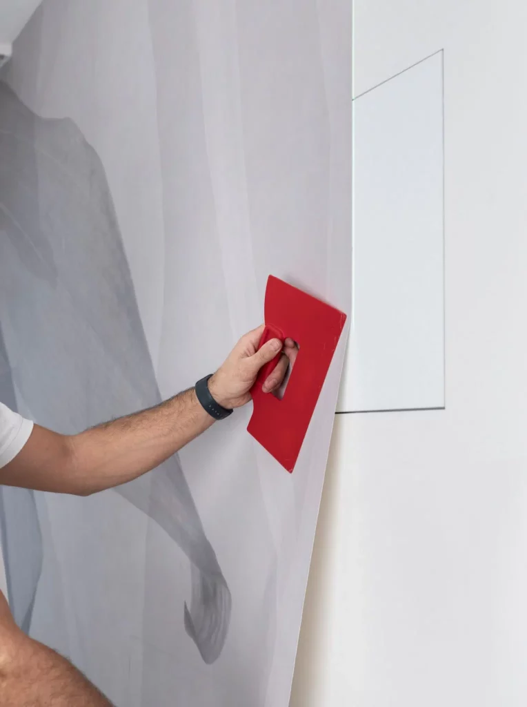 Application du papier peint sur le mur et le placard affleurant